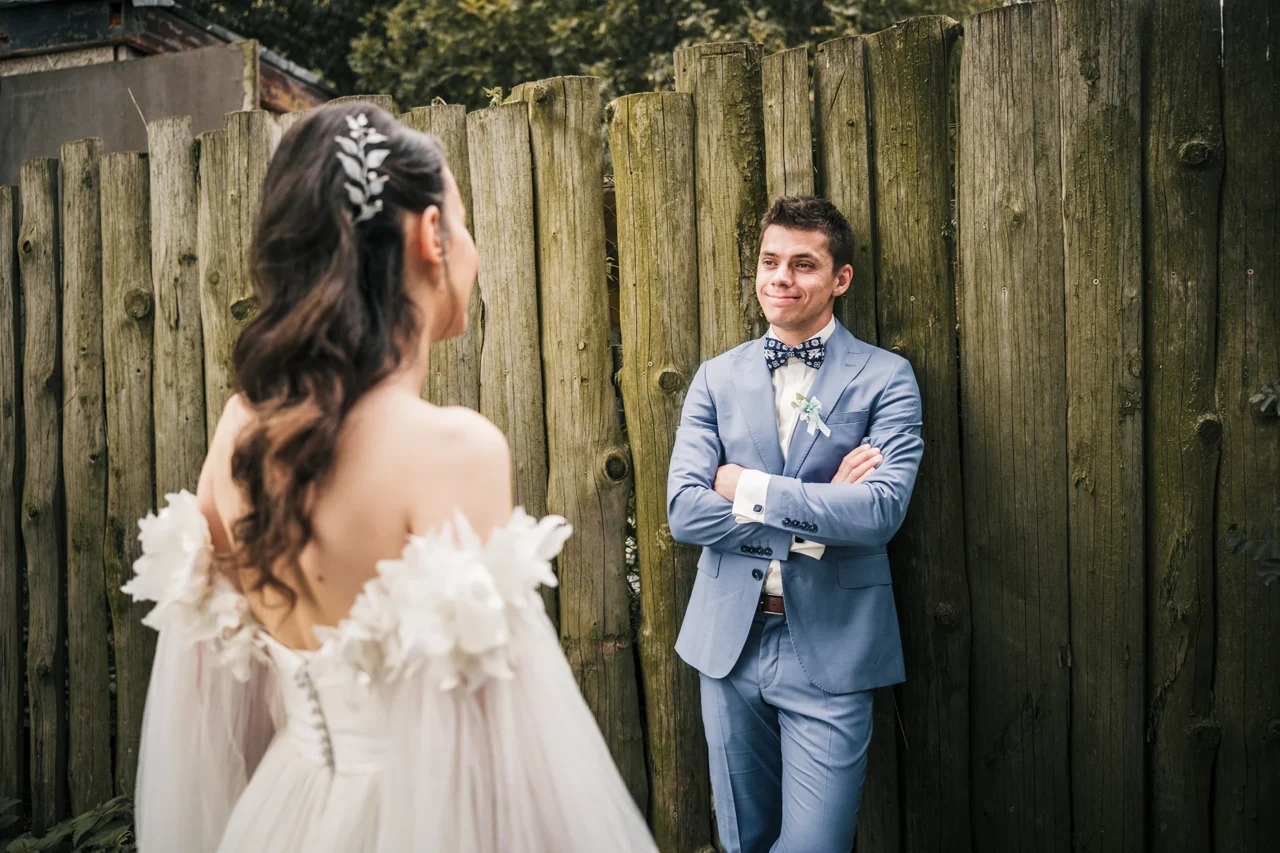 ženich se opírá o plot a dívá se na nevěstu